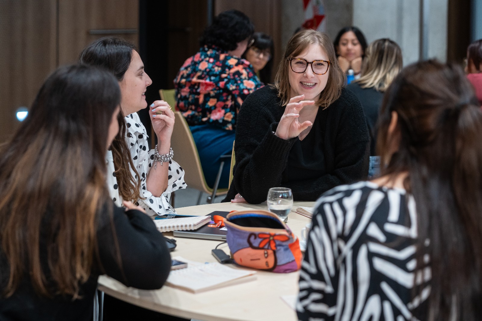 Un grupo de mujeres conversa alegremente en una mesa de trabajo.