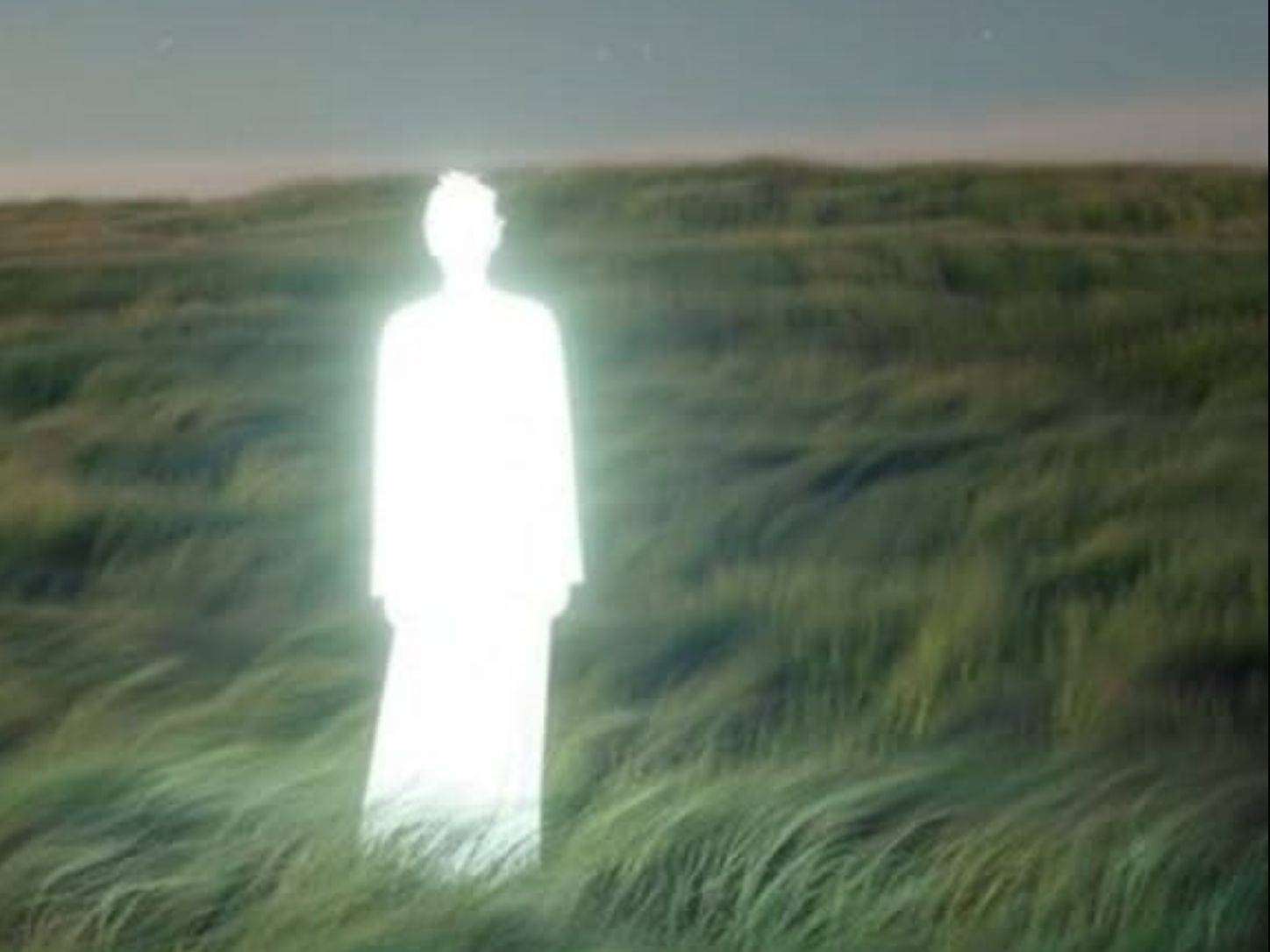Figura luminosa en un campo al atardecer
